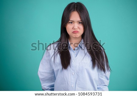 Disappointed young asian woman with pursed lips looking at camera as if she is upset not getting what she wants