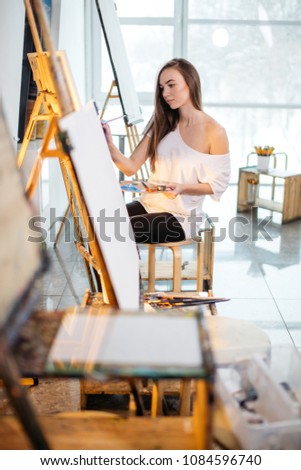 Artist, a European girl painting on easel at art school. Concept teaching painting.