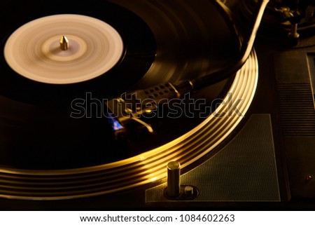 Vintage turntable with movement effect on the vinyl record while playing inside a disco. Royalty-Free Stock Photo #1084602263
