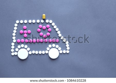Medicine, healthcare and pharmacy concept - different pills and capsules of drugs in shape of car ambulance.