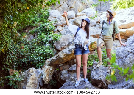 Two beautiful young girls travel in the mountains and enjoy the view of the landscape of green trees.