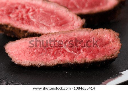 black angus rare steak sliced dark plate on a black background