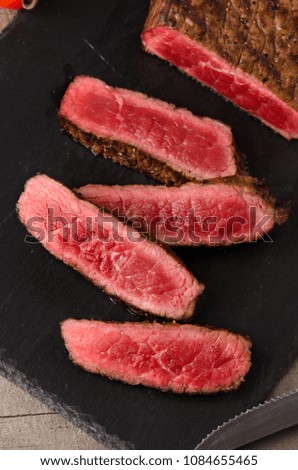 black angus rare steak sliced dark plate on a gray wooden background