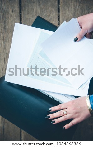 The top view on the documents in the black folder. Paperwork. The sheets of paper in hands.