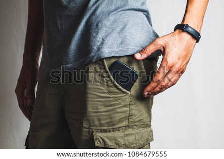 close-up of a hand about to take a ringing phone from a pant pocket Royalty-Free Stock Photo #1084679555