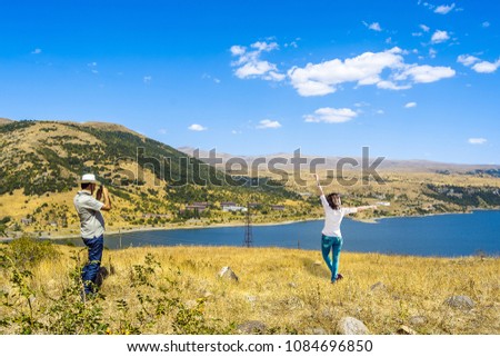 Traveler photographer makes a photo of a young girl on a lake background