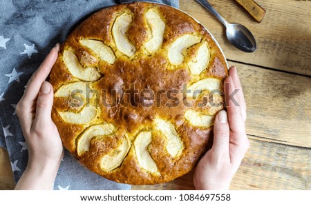 Apple cake on the plate and milk on a wooden table. female hand. Top view