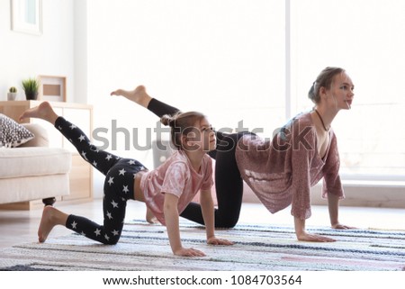 Young mother and her daughter practicing yoga at home