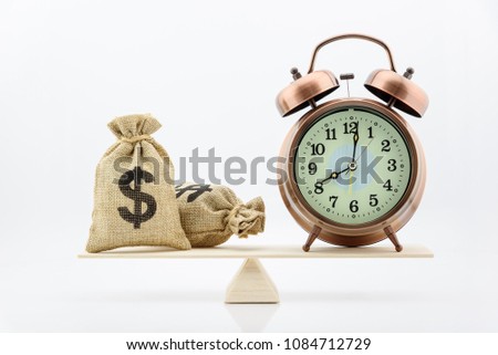 Time is money or time saving concept : Dollar or cash in hessian bags / burlap sacks and vintage clock on wood balance scale, depicts the importance of time and money that everyone should balance well