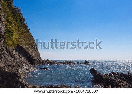 rocky sea shore with pebble beach, waves with foam