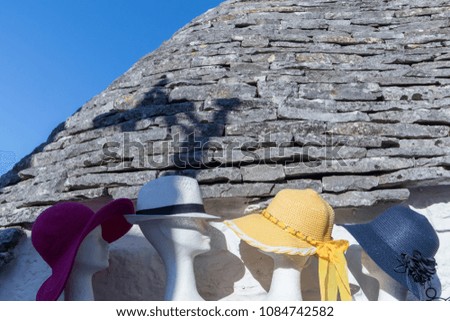 Four hats with different colors, near a house wall