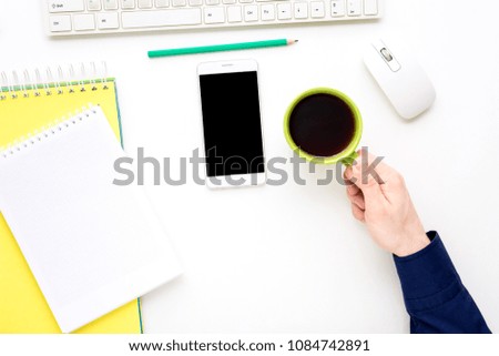 white desk, male hands, man holding a cup of coffee, white smart phone lies on the desk,  office supplies,  white background with copy space, for advertisement, top view