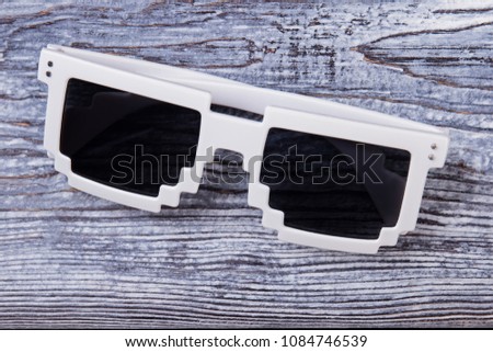 Pixel sunglasses close up. Black eyeglasses with white frame on wooden desk surface.