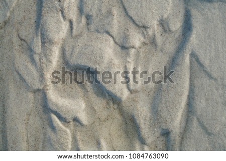 Textured close-up background with wet brown sea sand, combined with flowing water, placed in a beautiful pattern