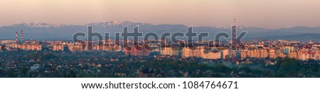 Wide panorama, aerial view of Ivano-Frankivsk city, Ukraine. Scene of modern tourist city with tall buildings, residential quarters and green streets on background of distant Carpathian mountains.