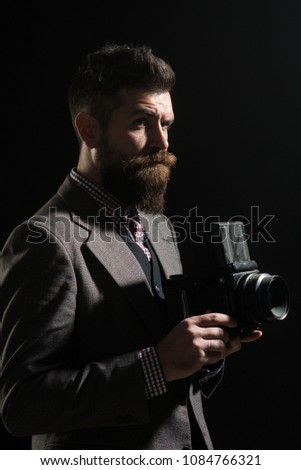Serious bearded man with retro camera in tweed vintage dress. Vintage photography concept - man in retro style with vintage photo camera. Silhouette of man with beard & mustache with retro old camera.