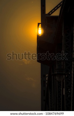 A collection of sun photos as it sets behind foggy clouds near a bridge