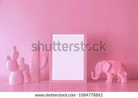 The design pink desk with cacti, elephant figure and photo frame. Modern mock up and lightbox concept.