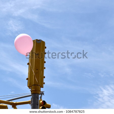 Pink balloon floating next to a traffic light on a clear sunny day