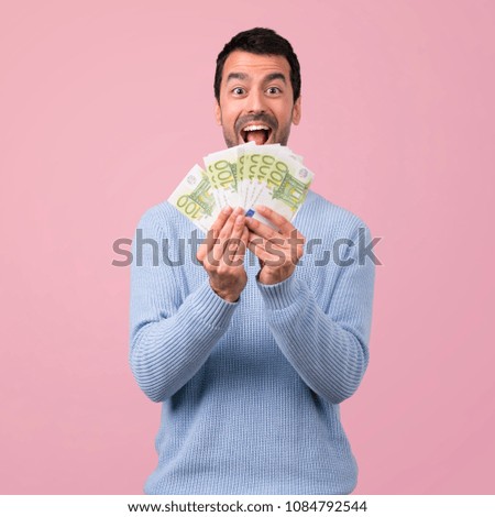 Man with blue sweater taking a lot of money on pink background