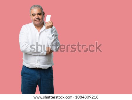 Middle aged man smiling confident, offering a business card, has a thriving business, copy space to write whatever you want