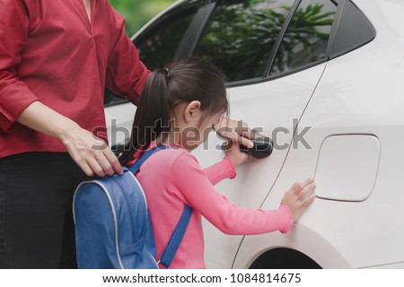 Back to school concept, Beautiful young asian mother or parent helping daughter or pupil to getting in the white car to ride to school, Selective focus. Royalty-Free Stock Photo #1084814675