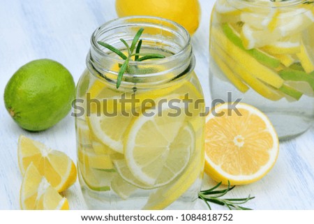 Detox water with lemon and rosemary in a jars on wood table