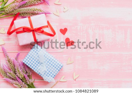 Happy mother's day concept. Top view of gift box with flower and tag with Love you MOM text on wooden block with pink handmade heart on on pastel color bright pink and white wooden background.