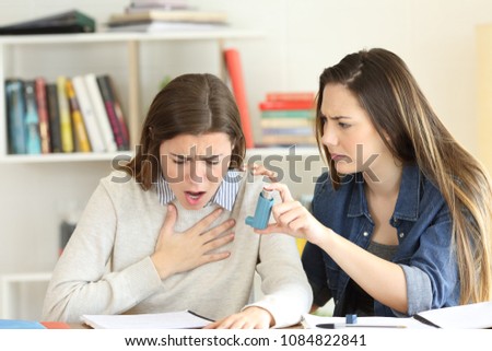 Student helping to her asmathic friend giving the inhaler during an asthma attack Royalty-Free Stock Photo #1084822841