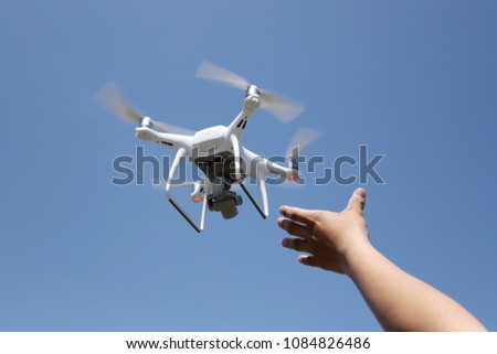 Hand catching drone aircraft in blue sky background, camera operator concept of aerial photography