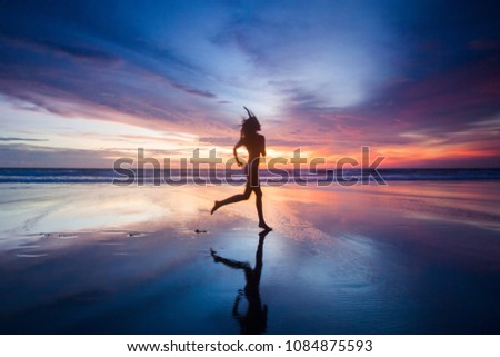 Woman in bikini running on the beach at sunset. Bali island, Indonesia