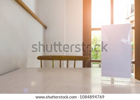 Stand mock up acrylic tent card menu frame on marble table in restaurant background.
Point of purchase advertising concept.
You can be used for message menu and  display products.