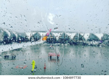 The raindrops are on the window of airplane.The blurred picture of runway that is raining outside.