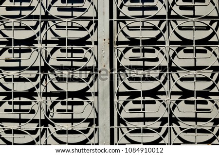 Close up of an old iron gate in front of a door with strong geometric patterns and rich shadows as seamless vintage background