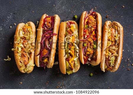 Hot dogs with a sausage on a fresh rolls garnished with mustard and ketchup and served with different toppings. Royalty-Free Stock Photo #1084922096
