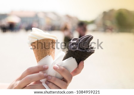 Woman's hands holding melting ice cream waffle cone in hands on summer light city background. Happy holiday concept. Close up photo.