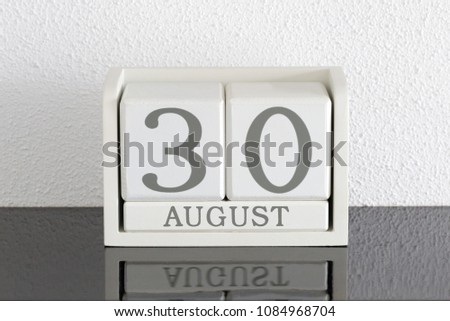 White block calendar present date 30 and month August on white wall background