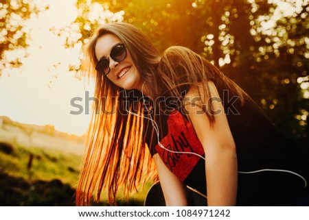 Portrait of a caucasian charming girl with sunglasses laughing at the sunset with light in her hair in the park.