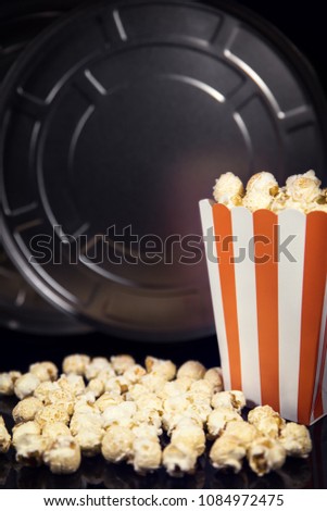 Reel and Popcorn in front of black, concept Cinema and Movie theater