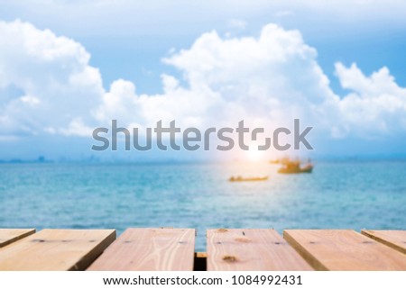 Wood table top on blur sea and boat with sunlight background. Summer, nature concepts. For montage product display or design key visual layout.