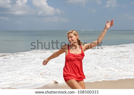 Young attractive woman dancing on a beach with the horizon and the sky in the background.
