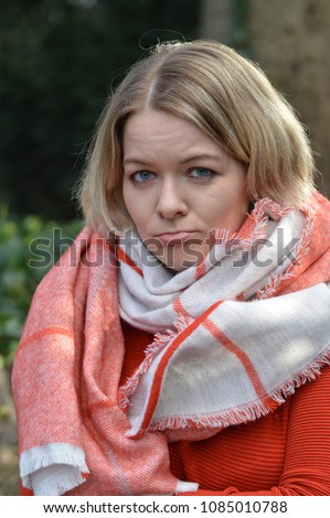 portrait of a young blond woman pursing her mouth quizzical with eye contact to the camera Royalty-Free Stock Photo #1085010788