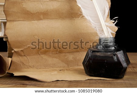 books, old paper and feather in an inkwell isolated on a black background