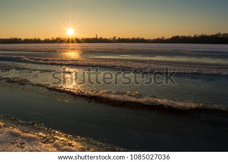 Winter evening by the river. The sunset and twilight were very beautiful. The photos are made on the river bank in Ukraine. The river is covered with ice and snow. The weather is frosty.
