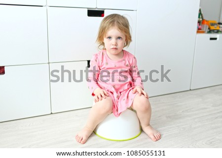 Lovely little 2 years girl sitting on potty at home