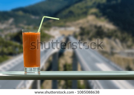 A glass of carrot juice in the cafe with view on speed highway through the window