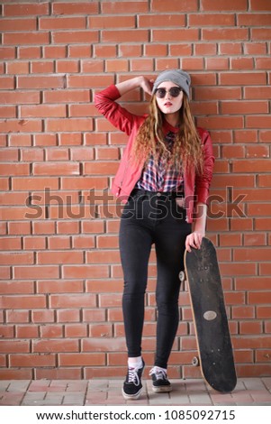 A young hipster girl is riding a skateboard.