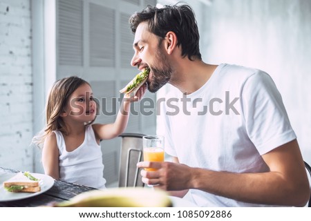 I love you, dad! Handsome young man at home with his little cute girl are having breakfast. Happy Father's Day! Royalty-Free Stock Photo #1085092886