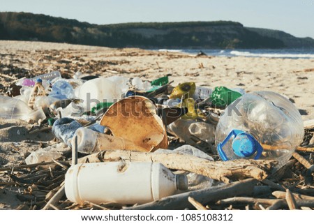 Spilled garbage on the beach of the big city. Empty used dirty plastic bottles. Dirty sea sandy shore the Black Sea. Environmental pollution. Ecological problem. Bokeh moving waves in the background