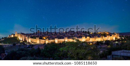 Panoramic view of the historic city of Avila, Spain with its famous medieval town walls surrounding the city with blue starry sky. UNESCO World Heritage. Called the Town of Stones and Saints